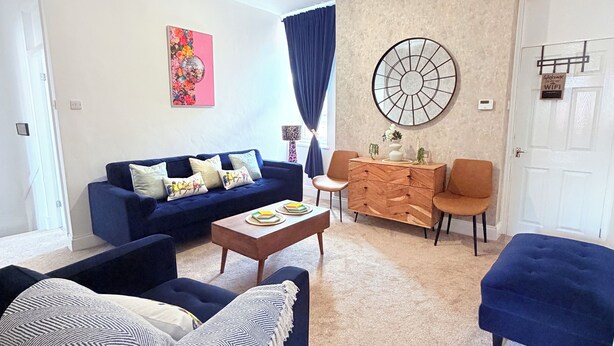 Sala de estar com sofá, mesa de centro e um objeto decorativo na parede.