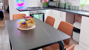 Cozinha moderna com mesa de jantar, cadeiras e um letreiro luminoso.