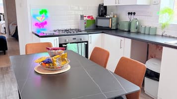 Ett modernt kök med ett matbord, stolar och en neonskylt.