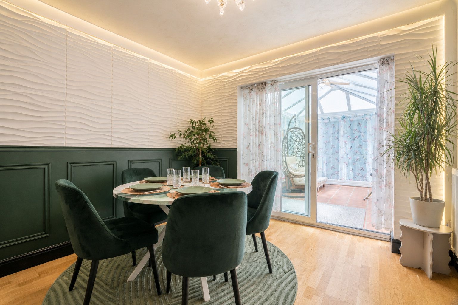 Un comedor con una mesa redonda, sillas y una planta en maceta.