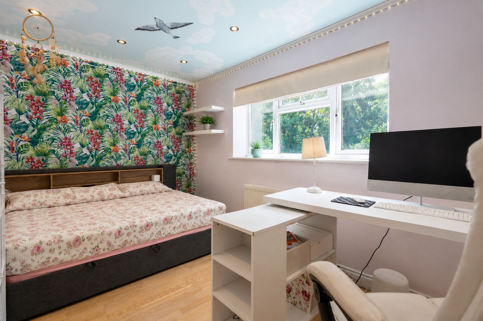 Een slaapkamer met een bed, een bureau, een computer en een raam.