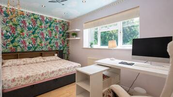 Een slaapkamer met een bed, een bureau, een computer en een raam.