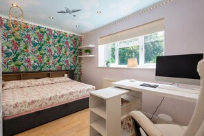 Ein Schlafzimmer mit einem Bett, einem Schreibtisch, einem Computer und einem Fenster.