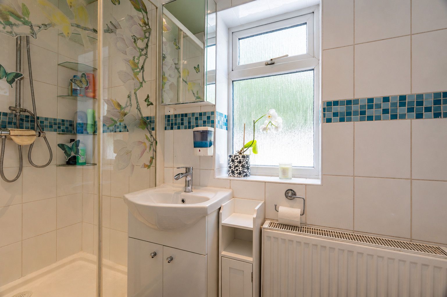A bathroom with a shower, sink, and window.