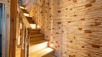 Un escalier en bois, avec un mur de pierre d’un côté.
