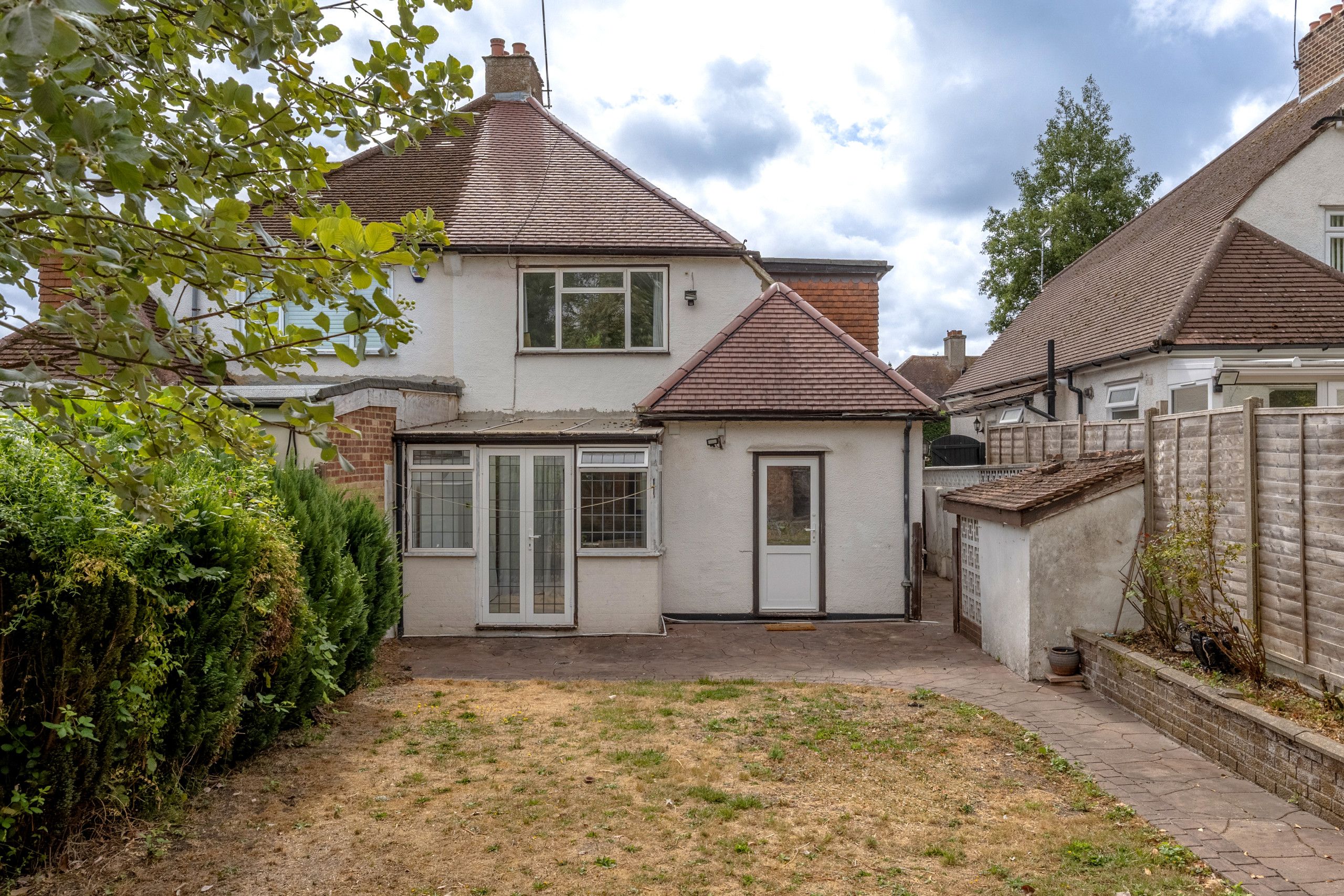 A residential property with a two-story house, a front garden, and a paved driveway.