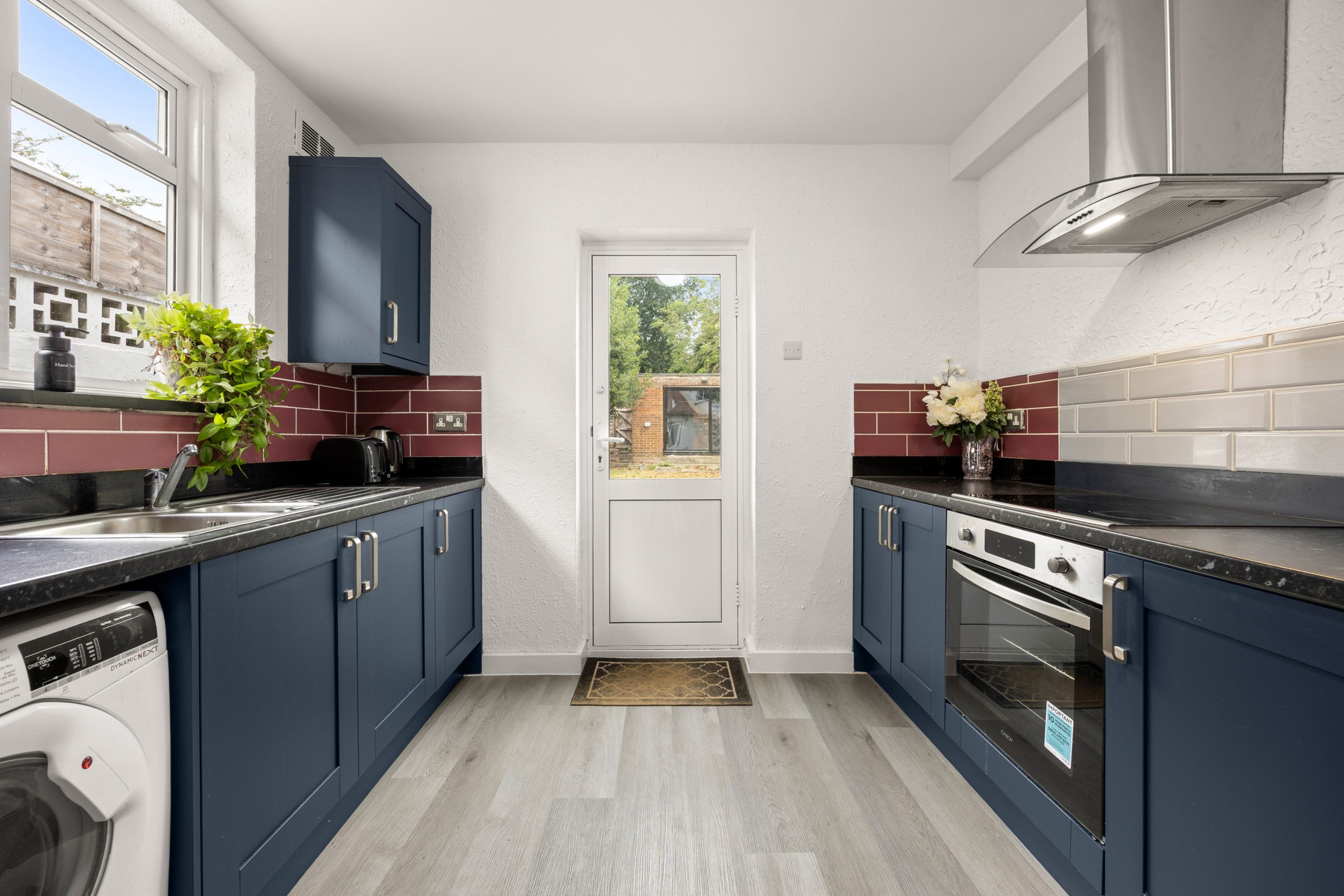 A modern kitchen with dark blue cabinets, a built-in oven, and a dishwasher.