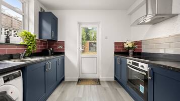 A modern kitchen with dark blue cabinets, a built-in oven, and a dishwasher.