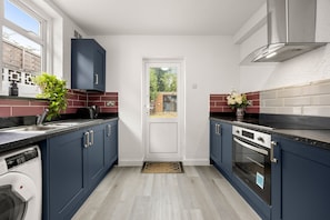 A modern kitchen with dark blue cabinets, a built-in oven, and a dishwasher. - Addington Road Croydon (Croydon)