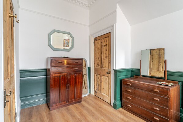 Ein Zimmer mit einem Holfischschrank, einer grünen Kommode und einem Spiegel an der Wand.