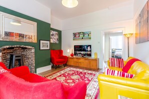 Ein Wohnzimmer mit Kamin, einem roten Sessel, einem gelben Sofa und einem Fernseher.