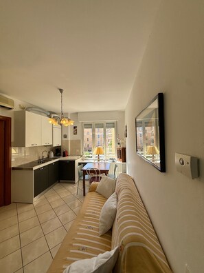 Una cocina moderna con comedor, sofá y un amplio ventanal con vistas a edificios.