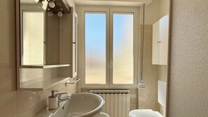A bathroom with a large sink, toilet, and a window with frosted glass. - Apartment 'Casa Di Fiorentino' with Balcony, Wi-Fi and Air Conditioning (Sanremo)
