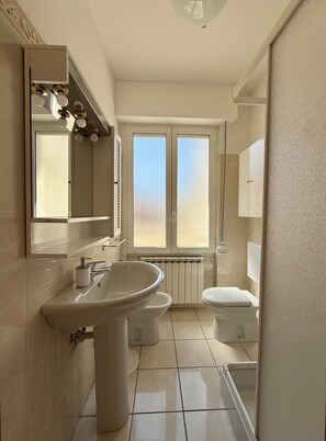Ein Badezimmer mit einem großen Waschbecken, Toilette und einem Fenster mit blickdichter Verglasung.