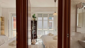 A hotel room with a bed, a wardrobe, a bathroom, and a view through an open door. - Apartment 'Casa Di Fiorentino' with Balcony, Wi-Fi and Air Conditioning (Sanremo)