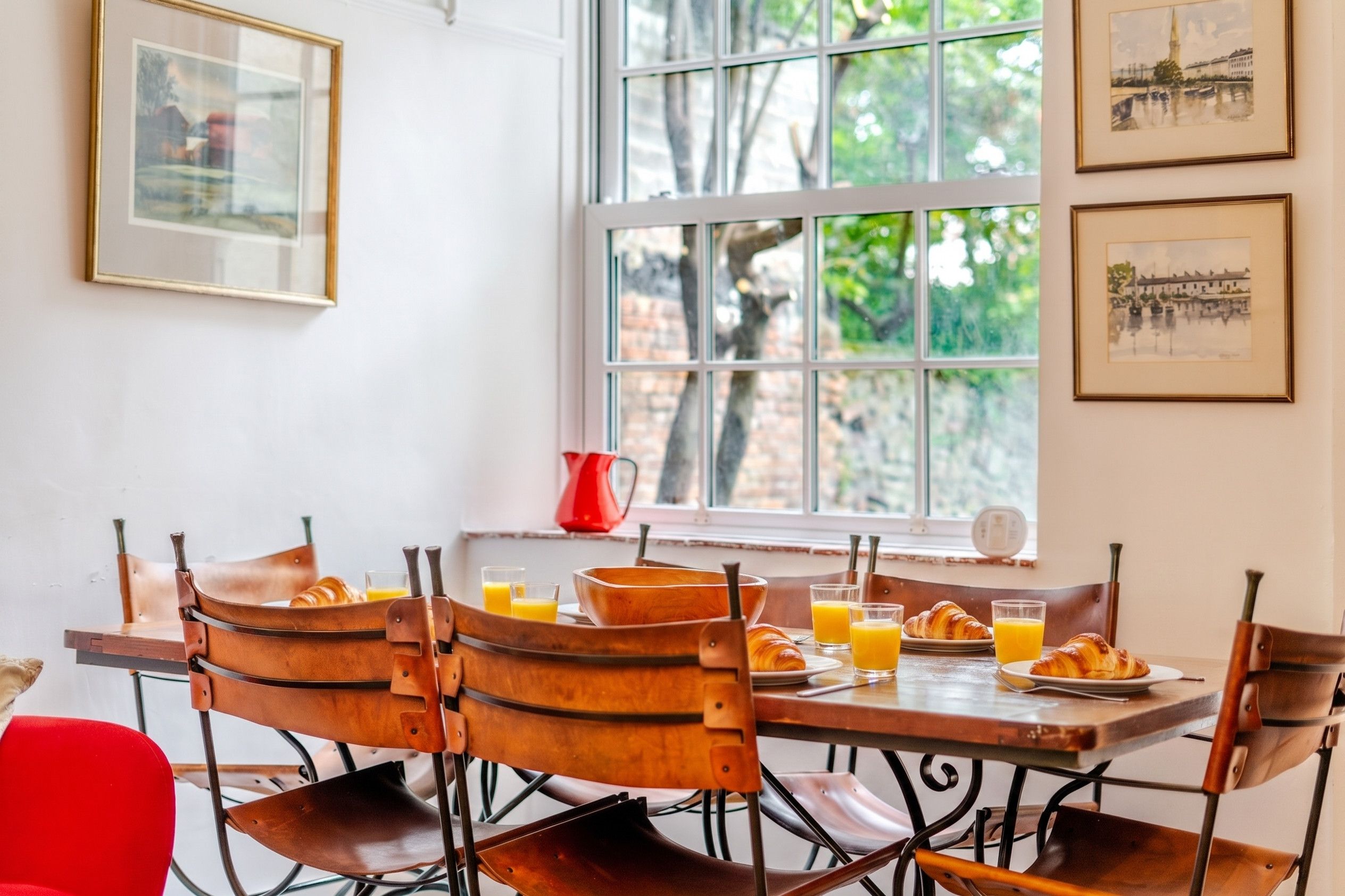 A breakfast setting with a table, chairs, and breakfast items.