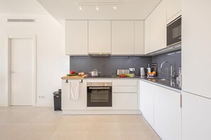 Eine moderne Küche mit weißen Schränken, einem eingebauten Ofen und einer Edelstahlspüle.