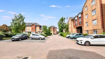 A residential area with brick buildings, a paved driveway, and parked cars.