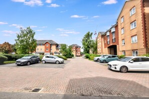 A residential area with brick buildings, a paved driveway, and parked cars. - Seager Drive Cardiff (Cardiff)