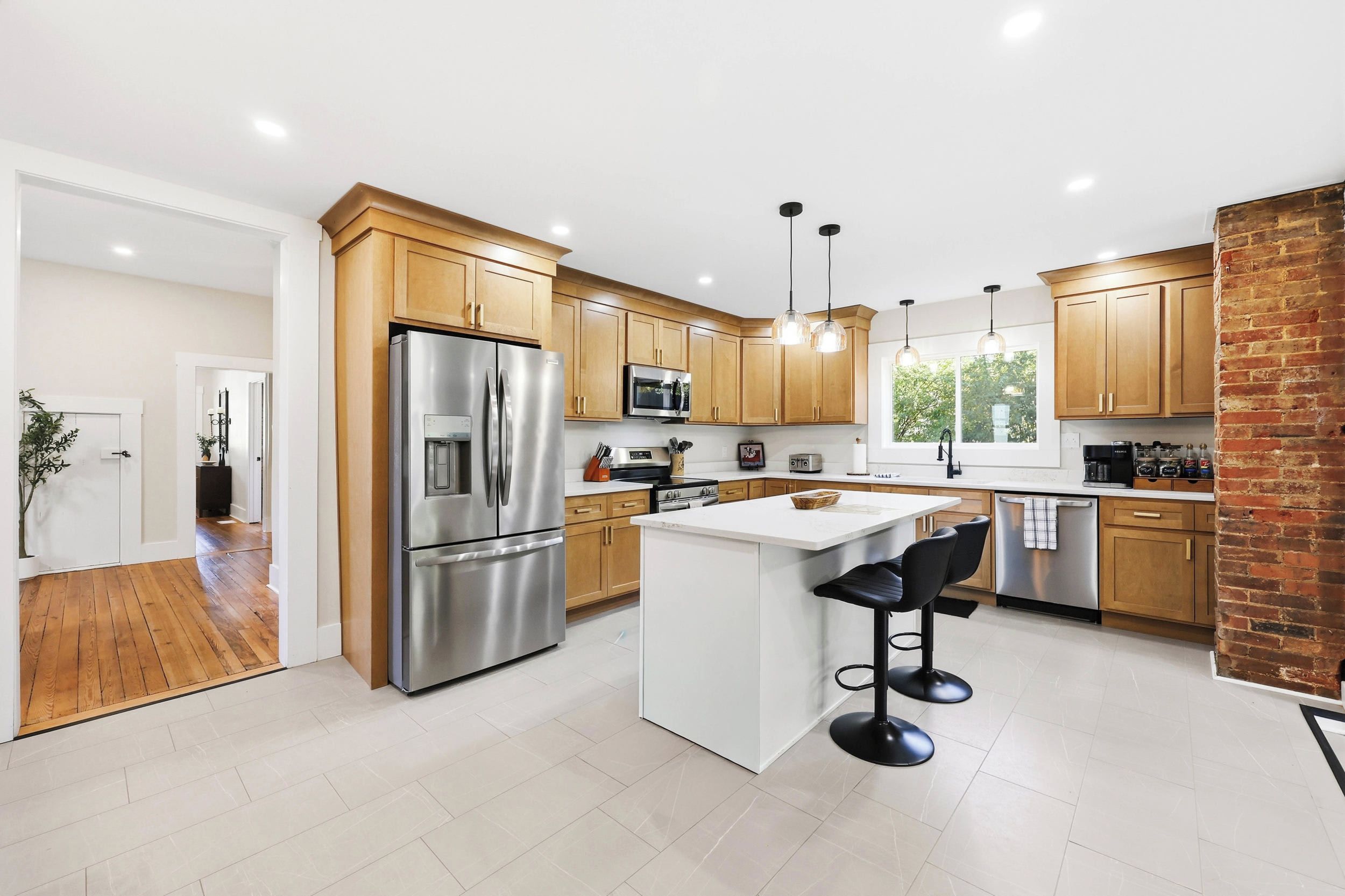 Una cocina moderna con electrodomésticos de acero inoxidable, armarios de madera y una isla central con taburetes de bar.
