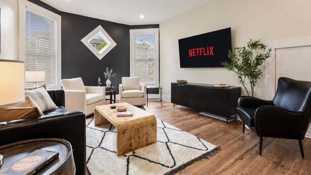 Een moderne woonkamer met een zwarte muur, een flatscreen televisie en een plafondventilator.