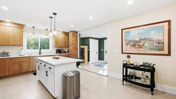A modern kitchen with wooden cabinets, a central island, and pendant lighting.