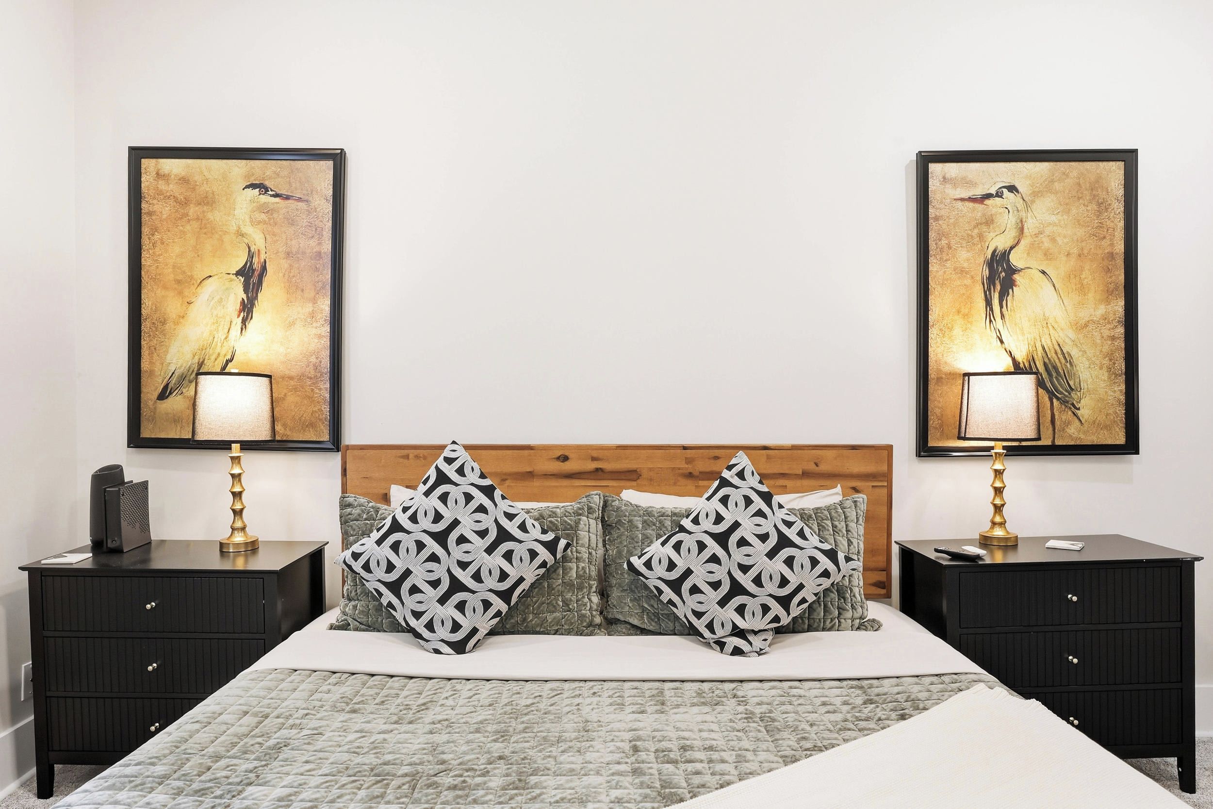 Une chambre à coucher comprenant un lit, deux tables de chevet, une tête de lit en bois et deux lampes fixées au mur.