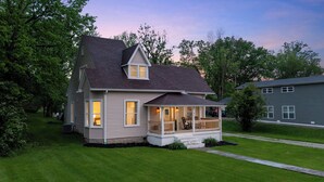Een tweelaags huis met een veranda, een garage en een verzorgd gazon.