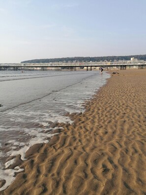 A beach with a sandy shore, a pier in the background, and a clear sky. - K-Suites - Modern Seaside Apartment in Weston-super-Mare – Steps away from Beach & Attractions (Weston-Super-Mare)
