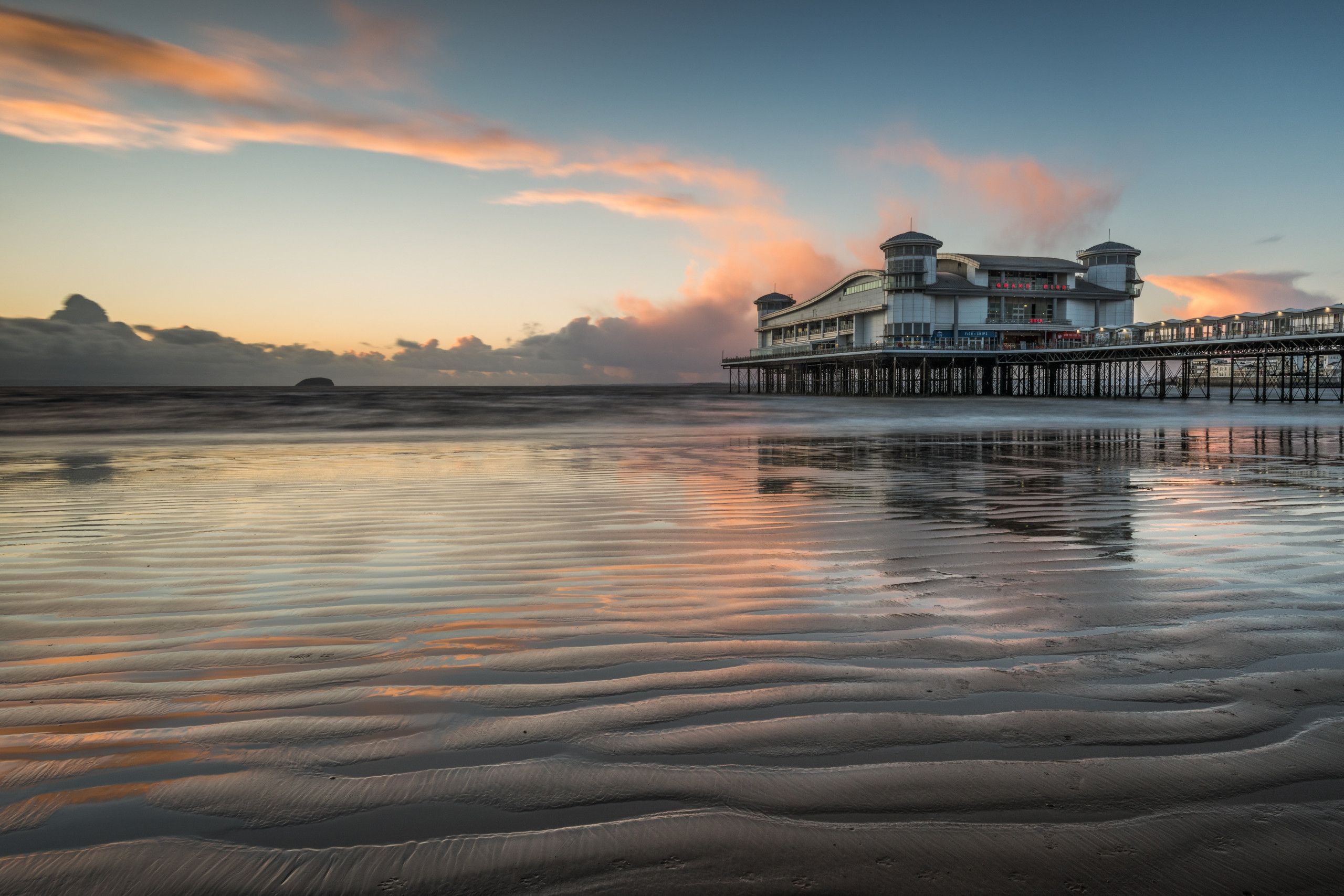 A waterfront hotel with a pier extending into the water, featuring a large building with multiple levels and a distinctive architectural design.
