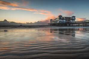Ein Hotel am Wasser mit einer Pier, die sich ins Wasser erstreckt, mit einem großen Gebäude in mehreren Ebenen und einem markanten architektonischen Design.