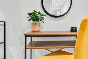 A wooden table with a potted plant, a round mirror, and a small container. - K-Suites - Modern Seaside Apartment in Weston-super-Mare – Steps away from Beach & Attractions (Weston-Super-Mare)