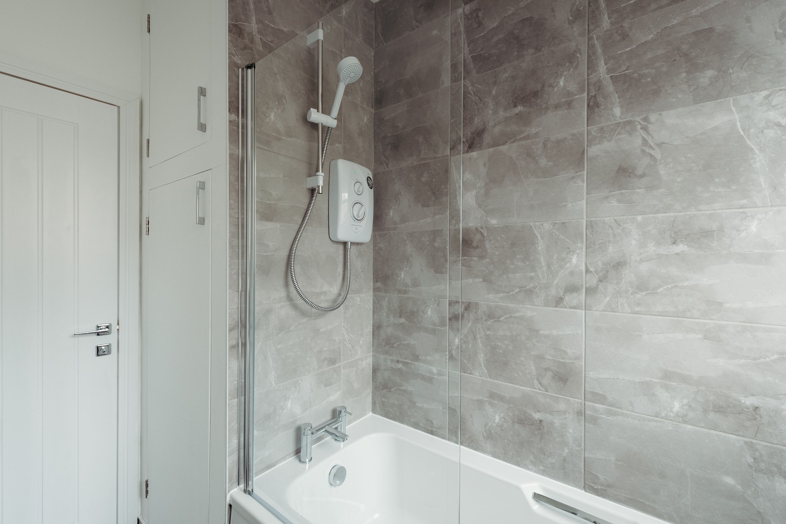 A modern bathroom with a bathtub, a shower with a handheld showerhead, and a control panel.