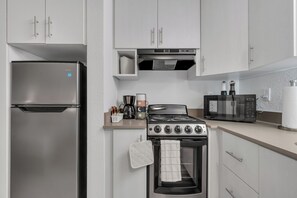 A modern kitchen with stainless steel appliances, including a refrigerator, stove, and microwave. - Cozy Suite Near Disney + Universal (Kissimmee)