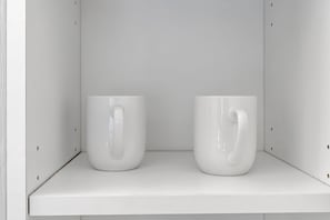 Two white ceramic mugs with handles on a white shelf. - Cozy Suite Near Disney + Universal (Kissimmee)