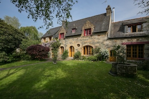 A stone house with a well-maintained lawn and a stone fountain. - Rooms 2 & 3 Moulin Du Tourous (Plouédern)