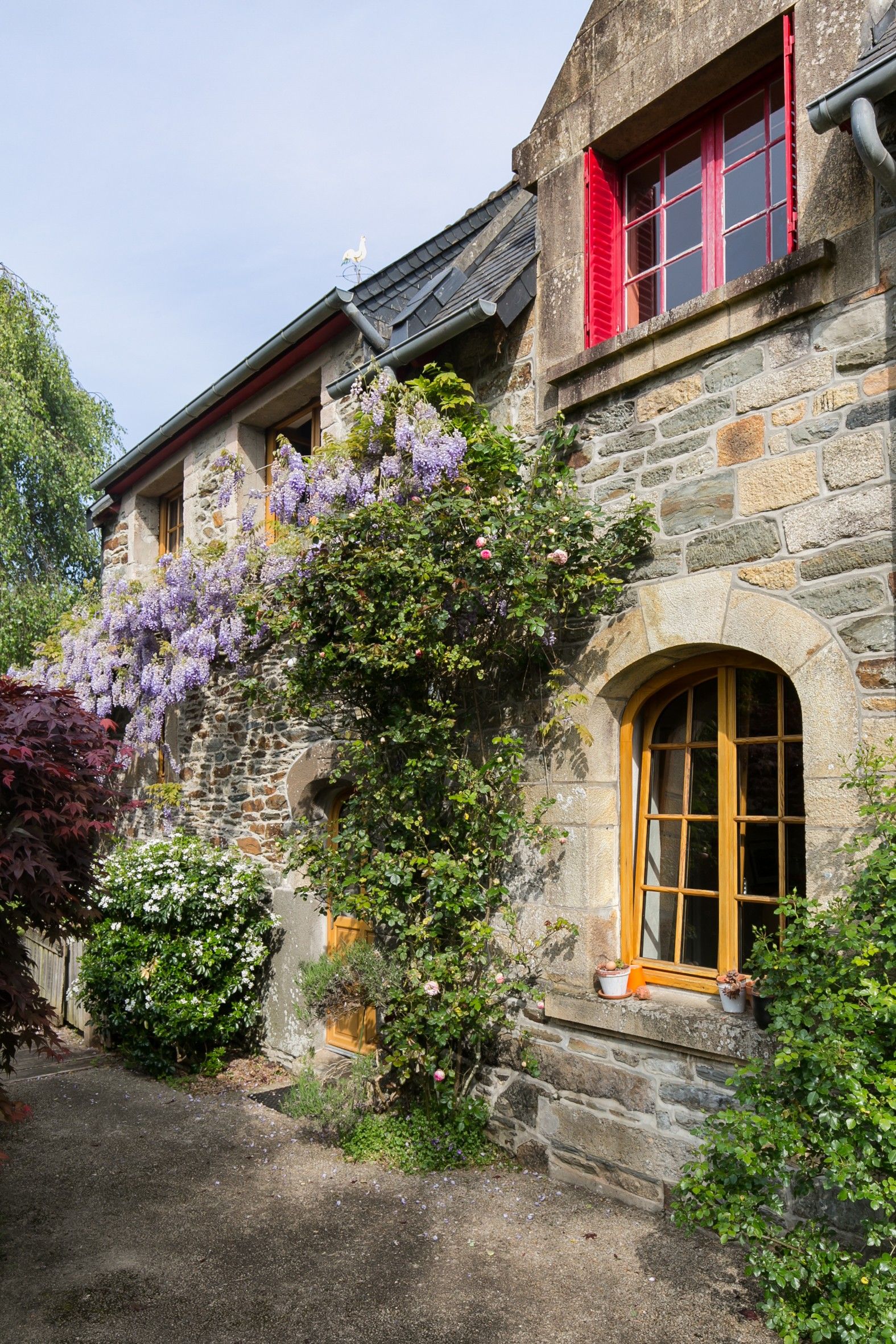 Ein Steinhaus mit einem roten Fenster und einer Holztür.