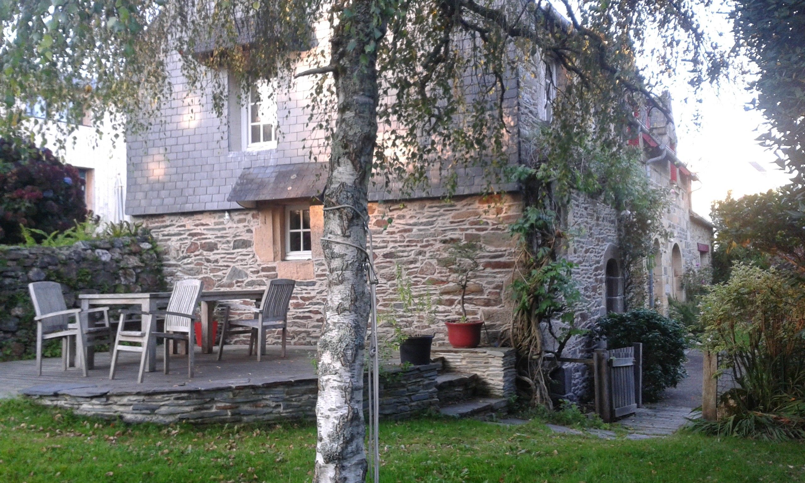 A stone building with a patio area, outdoor seating, and potted plants.