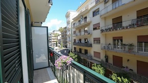 A residential building with multiple balconies, a green awning, and a clear sky. - Ricomincio da Tre (Sorrento)