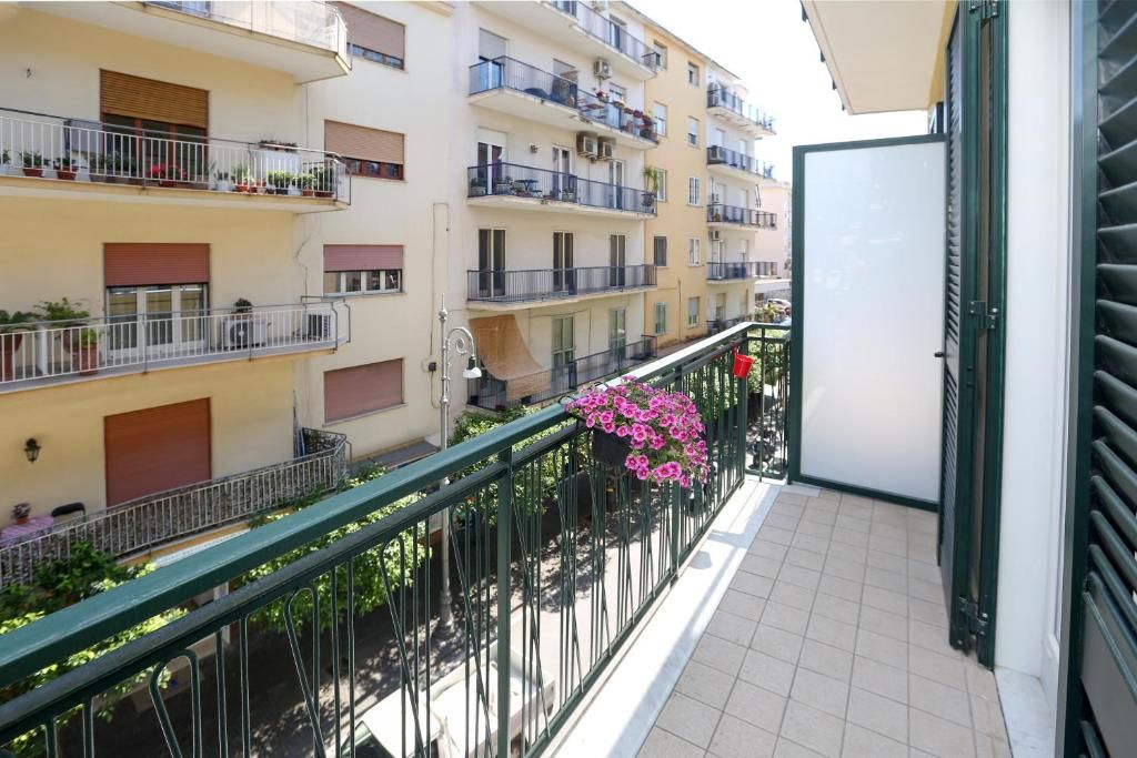 A multi-story residential building with balconies, railings, and potted plants.