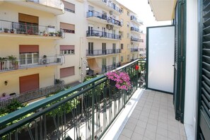 Un edificio residencial de varios pisos con balcones, barandillas y plantas en macetas.