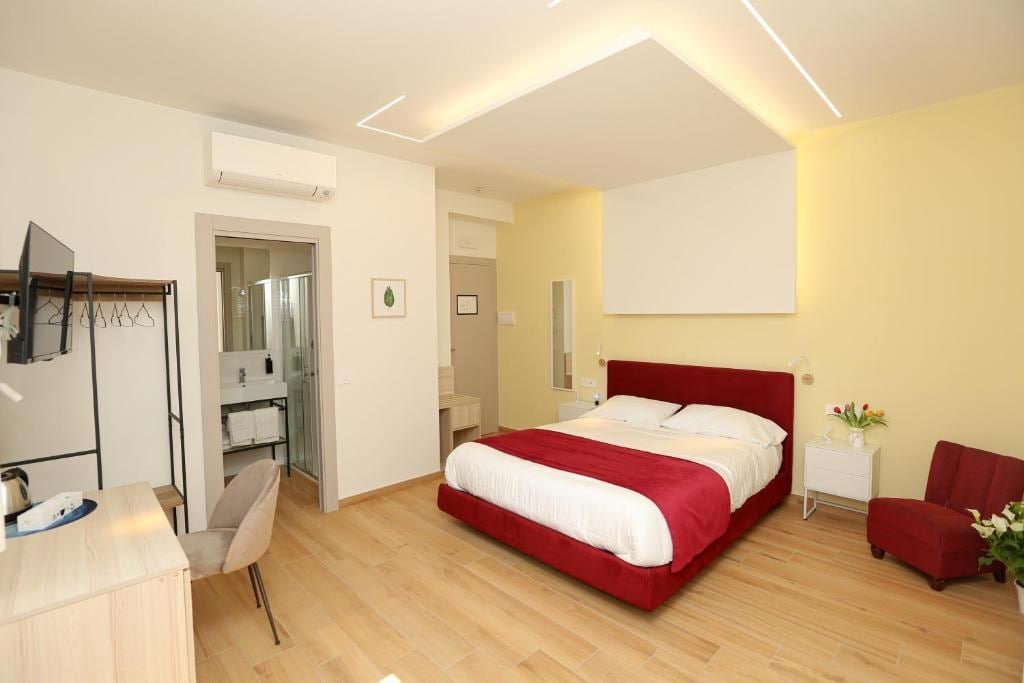 Ein modernes Schlafzimmer mit einem großen Bett, Nachttischen, einem Schreibtisch und einem Sessel.