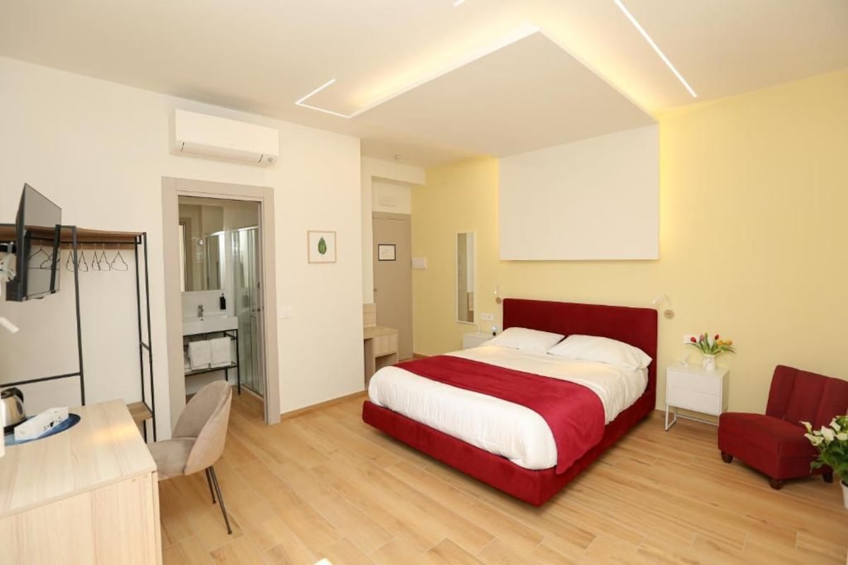 A modern bedroom with a large bed, bedside tables, a desk, and a chair.