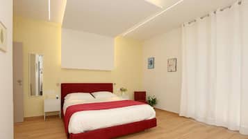 Un dormitorio moderno con una cama roja, una mesita de noche, un espejo y una ventana con cortinas.