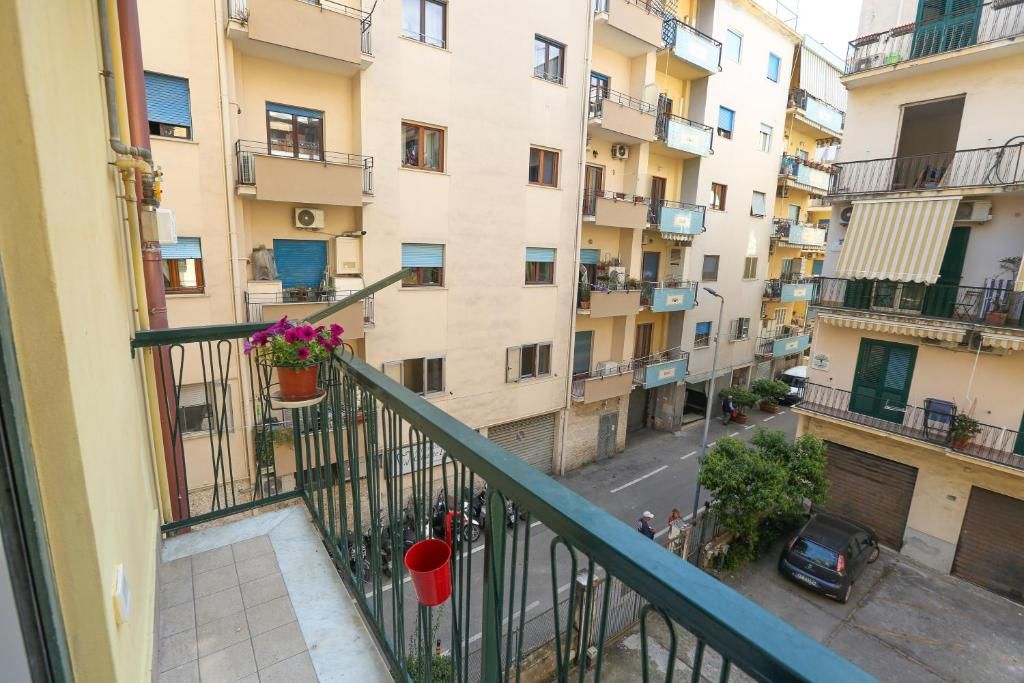 A multi-story residential building with balconies, a street view, and a parked car.