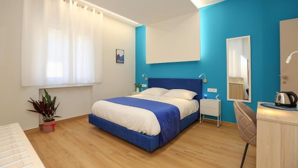 A bedroom with a bed, bedside tables, a mirror, a plant, and a desk with a kettle. - Ricomincio da Tre (Sorrento)