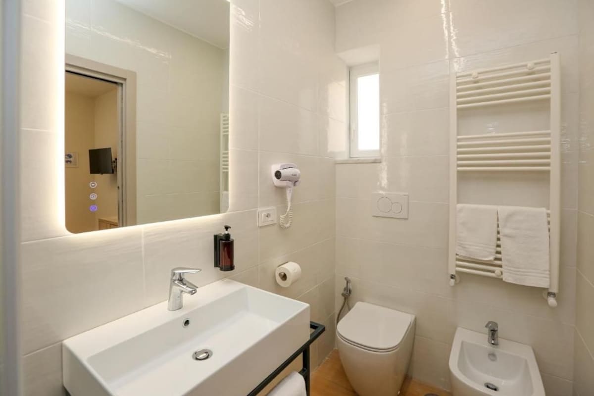 A bathroom with a sink, toilet, bidet, and towel rack.