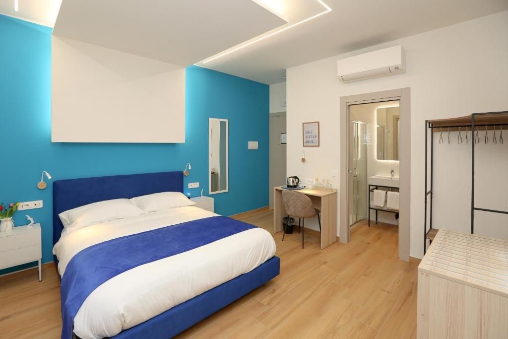 A modern bedroom with a large bed, a desk, and a walk-in closet.