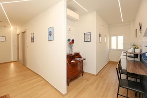 A hotel room with a wooden floor, a wooden dresser, a dining table with chairs, and framed pictures on the walls. - Ricomincio da Tre (Sorrento)