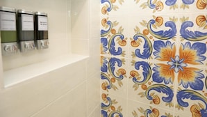 A bathroom with a tiled wall featuring a floral pattern and three dispensers labeled 'shampoo,' 'shampoo,' and 'body wash.' - Ricomincio da Tre (Sorrento)
